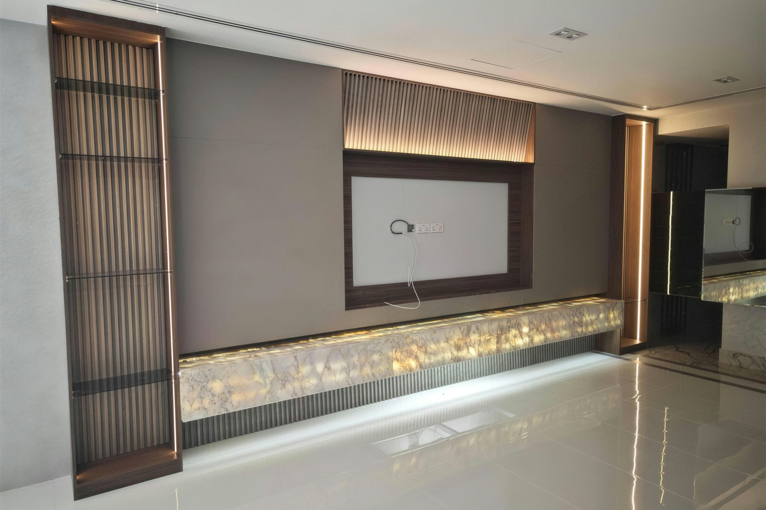 Media wall with backlit onyx shelf, fluted timber panelling and recessed lighting